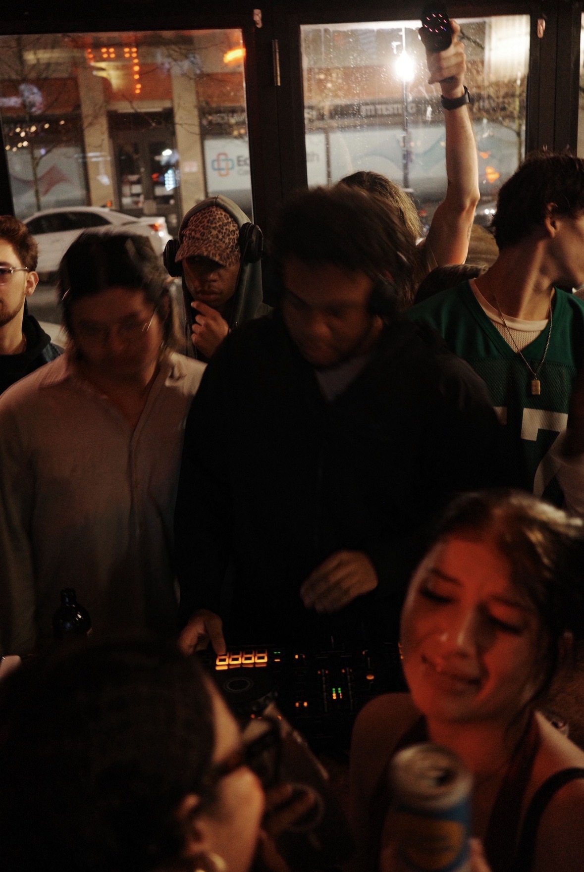 A close crowd gathered around a DJ controller at night