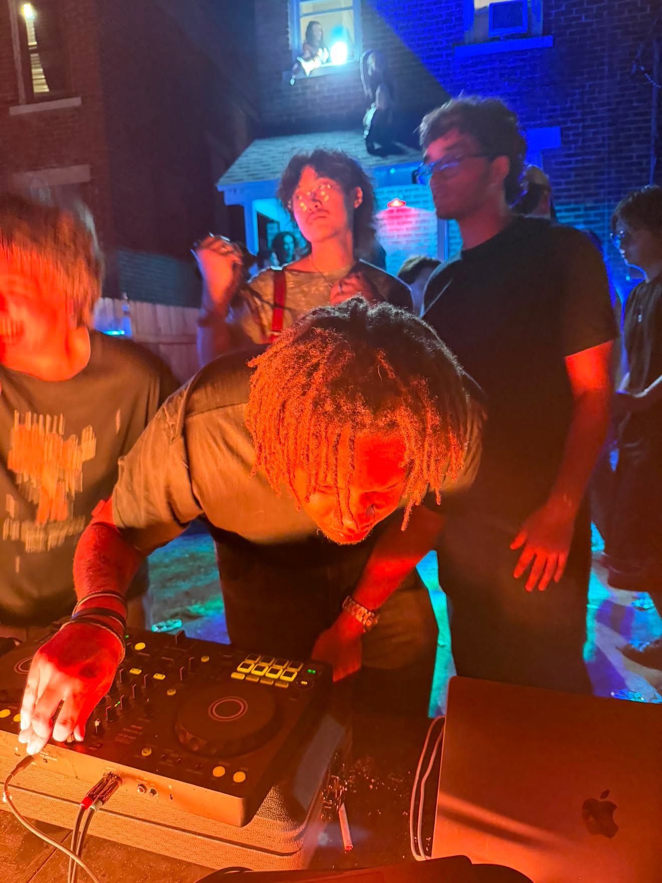 An outdoor DJ set lit in red and blue